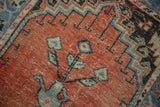 Distressed Oushak rug showing faded brick red, mint green tree of life design.