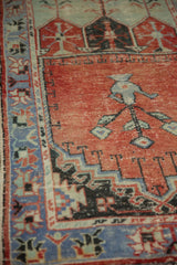 Close-up of distressed Oushak rug: faded brick red field, tree of life, blue serpent border.