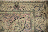 Corner of a vintage Kayseri carpet showing a scrolling blossom border in dusty rose and silver.