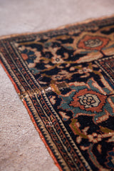 Antique Farahan Sarouk rug's intricate border showing Herati motif, aged pile, and edge restoration.
