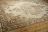 Angled view of a distressed Kars carpet's Rococo spandrel and low-pile texture.