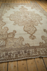 Angled view of the large shield-like medallion on a distressed vintage Kars carpet.