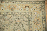 Corner detail of distressed Sivas carpet with palmette border, diamond vines, soft gold and blue.