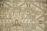 Corner close-up of a distressed Sparta carpet showing the serrated leaf and serpent geometric borders.