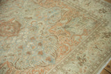 Scrolling vine and blossom motifs in soft sandalwood and slate blue on a low-pile vintage carpet.