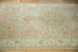 Soft, even wear across the pale blue and sandalwood floral patterns of a vintage Turkish carpet.