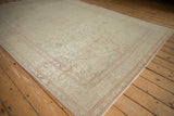 Angled corner of a distressed Kayseri rug showing its low-pile texture and raspberry border.