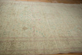 Angled view across the distressed Kayseri pile showing its mostly even wear and pale florals.