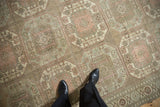 Floor view of a vintage distressed carpet showing its soft, low-pile texture and geometric guls.