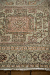 Detail of a distressed Turkish carpet's geometric guls in dusty rose, ivory, and brown.