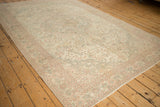 Angled view of a distressed Sparta carpet showcasing its scrolled vines and soft, faded blush tones.