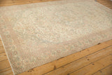 Angled view of the distressed vintage Sparta carpet showing scrolled vines in blush and brown.