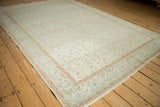 Angled view of a vintage distressed Kayseri carpet, showing its repeating floral pattern and ivory field.