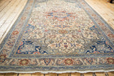 Ivory fringe, sapphire blue and terracotta palmette border, and ivory field with scrolling vines.