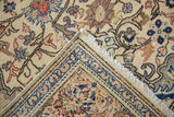 Kayseri carpet's flipped corner shows ivory floral field, sapphire blue border, and hand-knotted foundation.