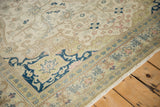 Corner view of the distressed Kayseri's navy spandrel, ivory field, and detailed borders.