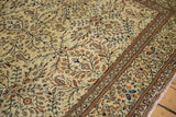 Angled view of vintage Sparta carpet's scrolled border and cream field with sapphire, terracotta florals.