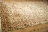 Intricate floral border and field on vintage Kayseri carpet corner in cream, aubergine, orange.