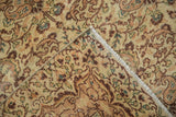 Kayseri carpet folded corner, showcasing cream, tangerine, and brown floral pattern and bound edge.