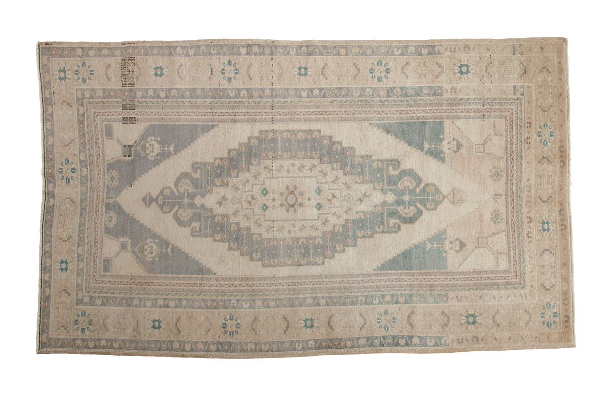 Distressed vintage Oushak carpet with a stepped concentric medallion in soft slate blue and sand.