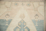 Low pile and stepped contour of a vintage Oushak carpet in soft sand and slate blue tones.