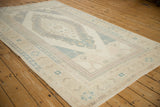 Angled perspective of a vintage Oushak rug with a pale, time-softened patina.