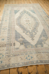 Angled view of a distressed Oushak carpet showing the elongated stepped medallion and border.