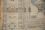 Intact side cord and geometric border with heavy abrashes on a vintage Oushak carpet.