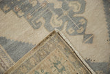 Hand-knotted foundation and side cord visible on the folded corner of a vintage Oushak carpet.