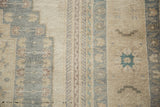 Close-up on the distressed Oushak's low pile, showing slate blue and sand color variation.