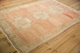 Corner of distressed vintage Oushak rug with pale melon field and ivory meandering border.