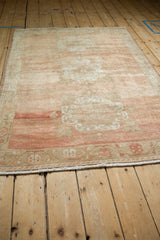 Distressed vintage Oushak rug's fringed bottom edge, revealing a vine border and melon-ivory abrashed field.