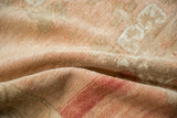 Heavily abrashed pile of the vintage distressed Oushak rug in soft cantaloupe and beige.