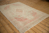 Corner of a distressed Turkish Kayseri rug, showing faded pink patterns and soft, worn pile.