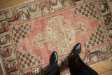 Distressed vintage Oushak rug with blush medallion, beige spandrels, and even pile wear.
