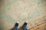 Distressed pile shows faded blue geometric patterns on a beige vintage Oushak rug.