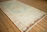Distressed vintage Oushak rug, faded blue-green medallion with geometric light brown border.