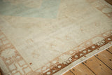 Distressed vintage Oushak carpet's faded ivory field, patterned brown border, and subtle blue.