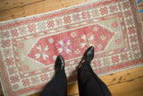 Vintage distressed Oushak runner with raspberry medallions, viewed from above to show its scale.