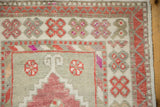Corner close-up of a distressed Oushak's geometric borders in dusty raspberry, ivory, and magenta.