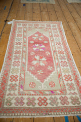 Angled view of a distressed Turkish Oushak runner displaying its raspberry red floral design.