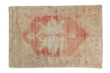 Vintage distressed Oushak rug with a faded raspberry medallion on a heavily worn, ivory ground.