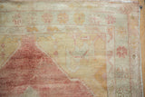 Even wear across the knot heads of a distressed Oushak rug in faded raspberry and ivory.