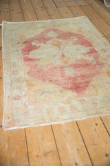 Angled view of a vintage Oushak rug highlighting its evenly worn pile and faded raspberry tones.
