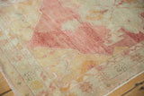 Abrashed, low-pile texture of a vintage Oushak rug in faded raspberry red, ivory, and saffron yellow.