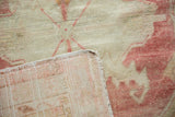 Corner detail of a distressed Oushak showing the hand-knotted reverse and faded, low-pile surface.