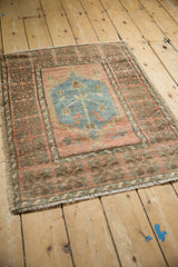 Distressed Oushak rug corner, showing even pile wear, intact selvage, and fringe.