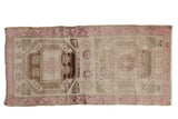 Distressed vintage Kurd runner with geometric medallions in brown and beige, framed by a bubble gum pink border.