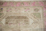 Low-pile texture and visible knot heads on a distressed rug with pops of fuchsia.