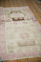 Angled perspective of a distressed Kurd runner showing its faded geometric gul medallions and pink border.